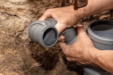 Bir muslukçu suyu boşaltmak için bir banyoya kanalizasyon boruları yerleştirir.