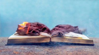 Yanmış sayfaları olan açık bir kitap. Kitaplara karşı barbar tavır.