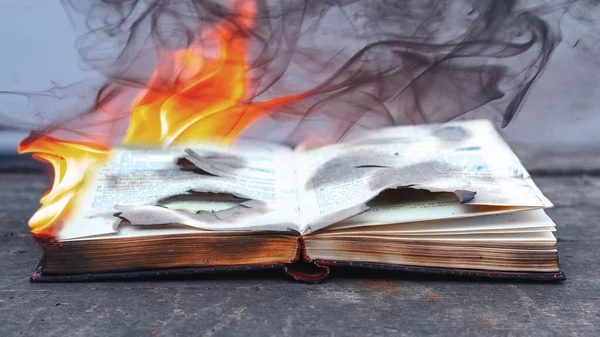 Burning books. An open book in flames and smoke