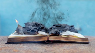 Kömürleşmiş sayfalar ve yanan dumanlarla dolu açık bir kitap.