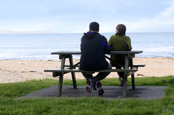 Young couple seat on opposite sides of park bench. — Stock Photo, Image