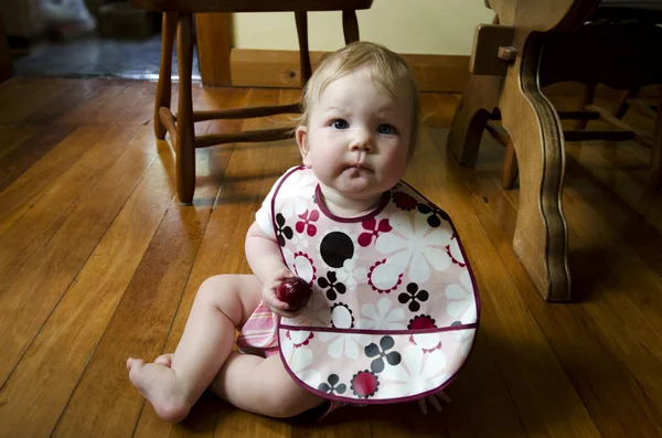 Blond baby girl eats plum — Stock Photo, Image