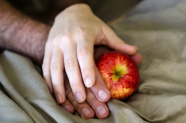 Las manos de hombre y mujer sostienen a Apple en la cama — Foto de Stock