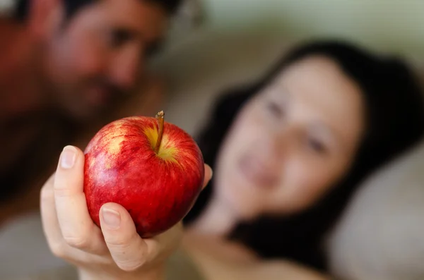 Man en vrouw houd apple in bed — Stockfoto