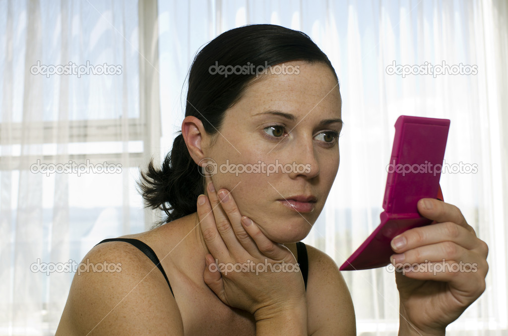 Young woman looks in mirror