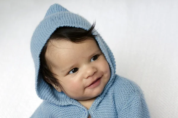 Newborn baby wearing blue cardigan smiles — Stock Photo, Image