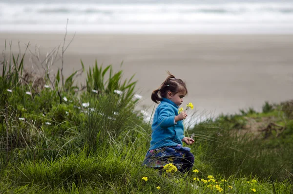 Kleines Mädchen hält gelbe Blumen in der Hand — Stockfoto