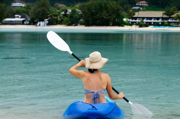 Jonge Kaukasische vrouw kajakken over turquoise water — Stockfoto