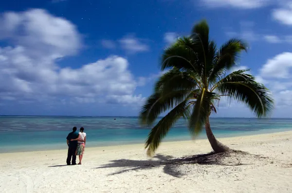 Young couple watches the stars at night on deserted tropical isl