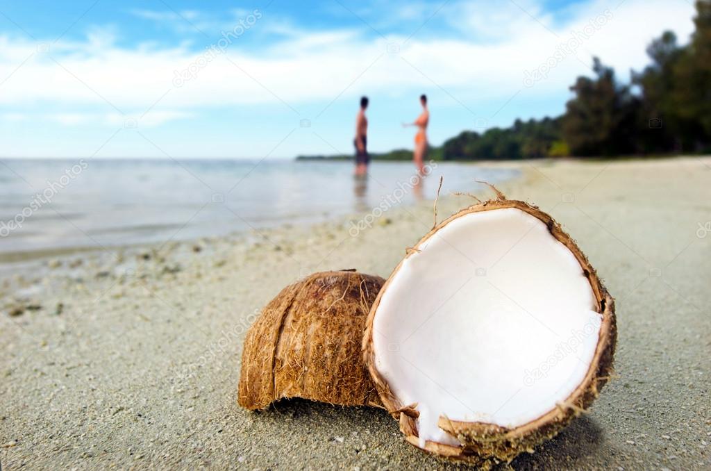 Opened coconut on sandy beach