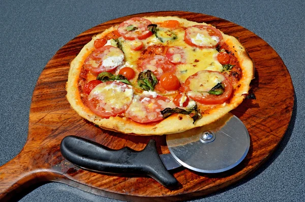 Pizza wooden board and pizza slicer — Stock Photo, Image