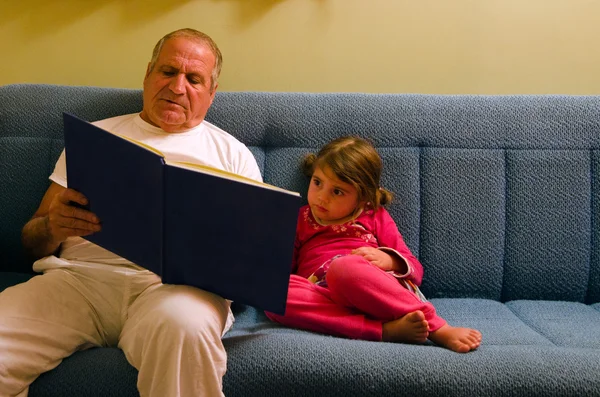 Grand-père et petite-fille lisent un livre avant de se coucher — Photo