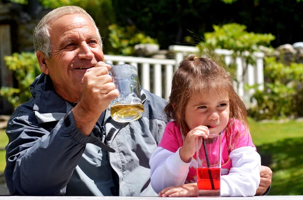 Grandfather drinks with his grandchild — Stock Photo, Image