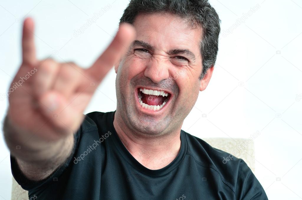 Mature man showing the devil thorns gesture sign  