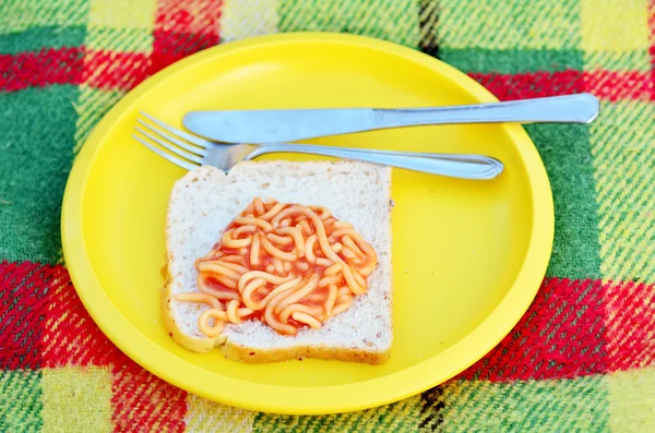 Caned spaghetti on bread slice — Stock Photo, Image