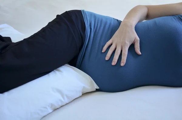 Těhotná žena na lůžku s polštář — Stock fotografie