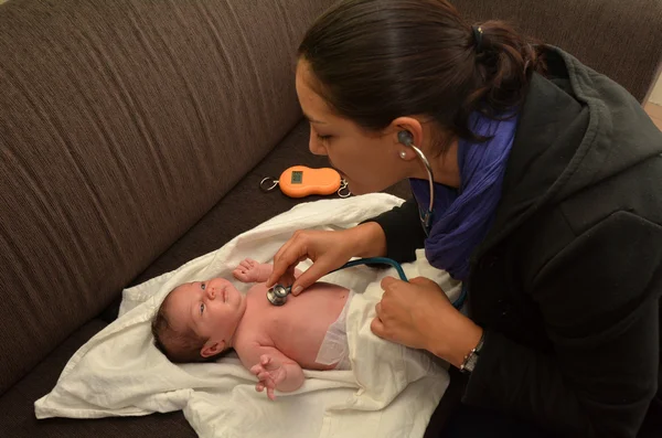 助産師は、生まれたばかりの赤ちゃんの心臓の鼓動をチェックします。 — ストック写真
