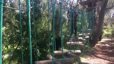 Sırdaş ve güçlü Avustralyalı genç kız (kadın 07 yaşında) ağaç tırmanma halatları kursunda yürüyor.