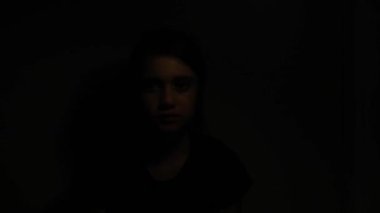 Üzgün kız (11-12 yaş) karanlıktan çıkıyor