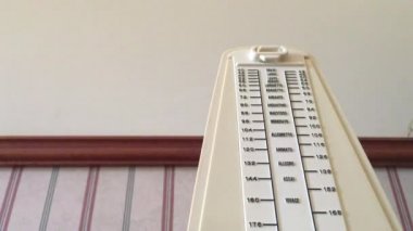 Piano metronome ticking against a vintage old house wall.Low angle. No people.Copy space
