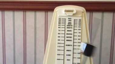 Piano metronome ticking against a vintage old house wall. No people. Copy space