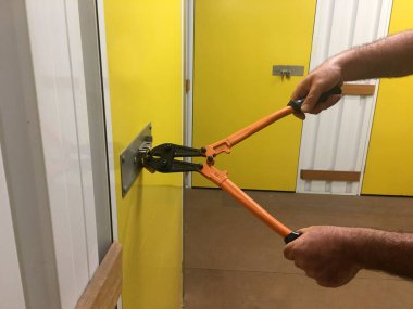 Hırsız elleri kilitli bir depoya girmek için kapı makası kullanıyor.