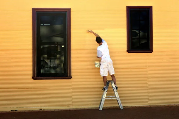 后视镜一个人在画一幢建筑物的大黄墙时的后视镜 — 图库照片