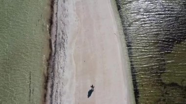 Aerial drone view of Australian woman walking on empty narrow sand bar in Shark Bay, Western Australia.