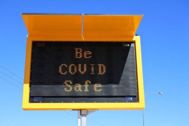 Be COVID Safe traffic sign isolated against clear blue sky.