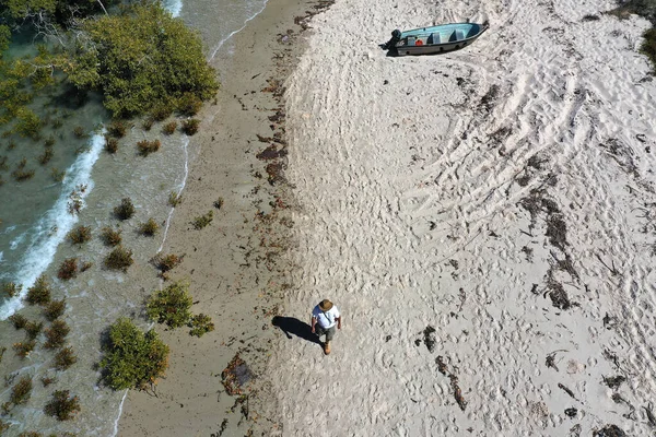 Aerial landscape view of Australian man walking on empty wild beach with a fishing boat in Cape Leeuwin in the Kimberley region, Western Australia