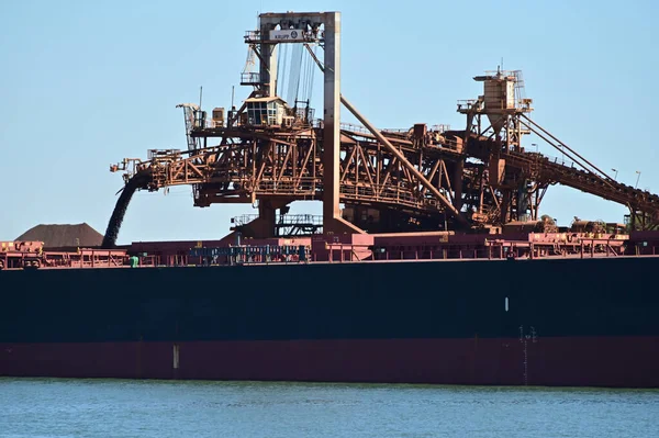 PORT HEDLAND, WA - JUNE 24 2022:Loading Berthed Iron Ore Ship, Port Hedland, Western Australia.The port exported 519,408,000 tonnes (1.1 trillion pounds) of iron ore (20172018).