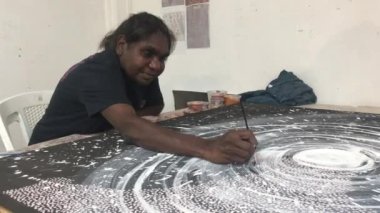 KUNURRA, WA - 06 2022: Etkin kıdemli Aborijin kadın sanatçı nokta boyama. Çağdaş yerli sanatçılar Avustralya 'nın en önemli sanat ödüllerinin çoğunu kazandılar..