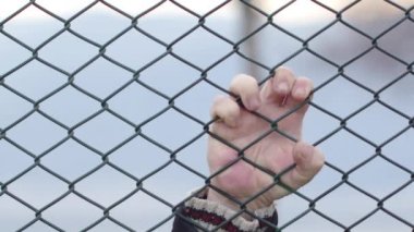 Metal tellerin arasından bakan umutsuz yaşlı adam.