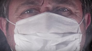Cerrahi maskeli yaşlı adamın dumanlı kameradan kameraya bakışının Dolly 'si..