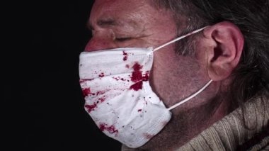 Kanlı cerrahi maskeli kıdemli adam kamera görüntülerine bakıyor..