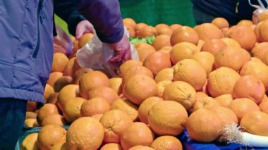 İnsanlar markette Orange Stall 'dan alışveriş yapıyor. Man Hand Süpermarkette Plastik Torbada Taze Portakal Alma ve Benekleme.