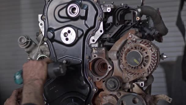 車の機械はコードレスドライバーの映像と修理店で修理されている車のエンジンの一部を締めます — ストック動画