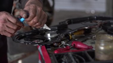Tamir atölyesinin motor bölümüne silikon dolgu maddesi uygulayan araba tamircisi.