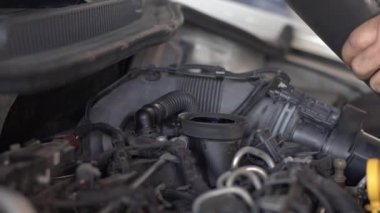 Oil change on a Car Fresh Oil Poured From a Black Plastic Bottle