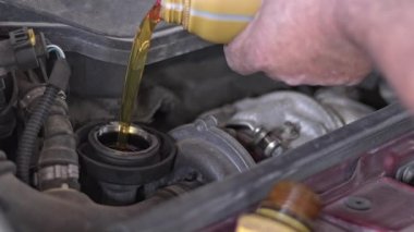 Motor yağı doldurma ve kapağını kapatma tamirhanesinde araba tamircisi..