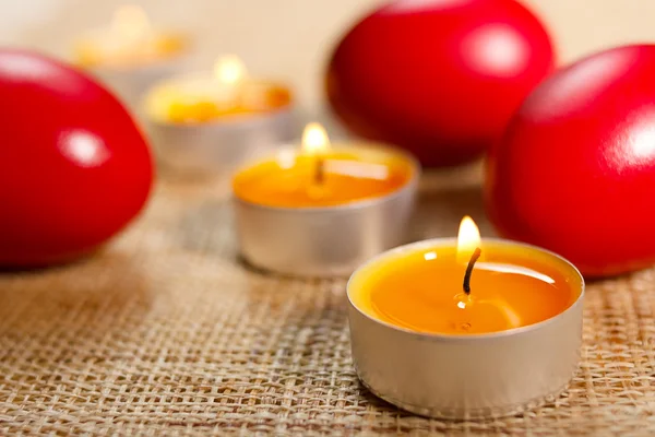 Primer plano de velas redondeadas colocadas entre tres huevos rojos — Foto de Stock