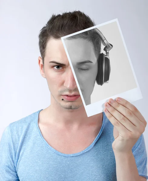 Junger Mann hält Foto mit sich mit Kopfhörer — Stockfoto