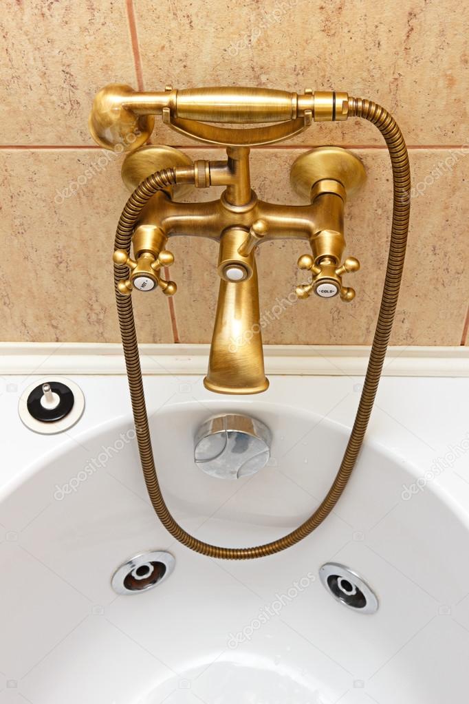 Vintage bathtub faucet and ceramic tiles in background