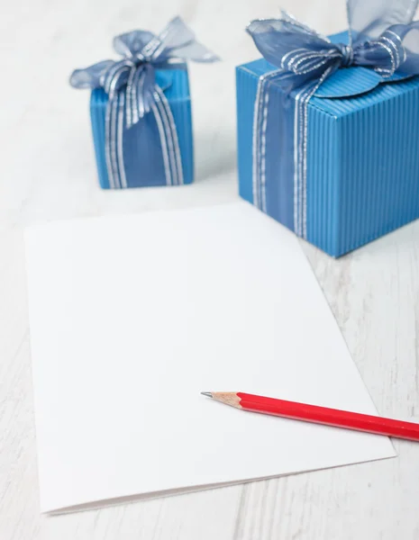Cartón con lápiz rojo delante de cajas de regalo azules — Foto de Stock