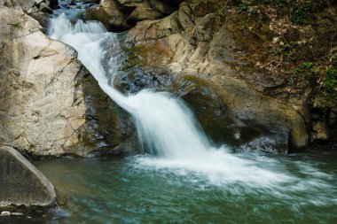 güzel cascade dağ kayaların üzerinden
