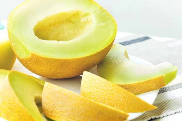 Melón amarillo en rodajas sobre plato blanco —  Fotos de Stock