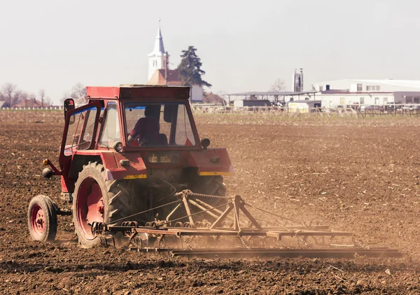 Foto červená traktoru, pracující terénu — Stock fotografie