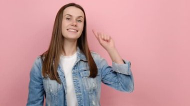 20 'li yaşlarda sevimli genç bir kadın. İşyerinin fotokopi odası tanıtım alanında el ele tutuşuyor. Kot ceket giyiyor, stüdyodaki pastel pembe arka plan duvarında izole edilmiş poz veriyor.