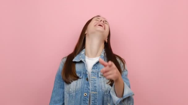 兴奋快乐的黑发女孩20岁的样子相机笑着看喜剧电影指尖上你 穿着斜纹棉布夹克 孤立在淡淡的粉色背景工作室 — 图库视频影像