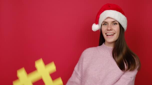Szczęśliwa Uśmiechnięta Młoda Kobieta Kapeluszu Świętego Mikołaja Trzymająca Żółty Symbol — Wideo stockowe